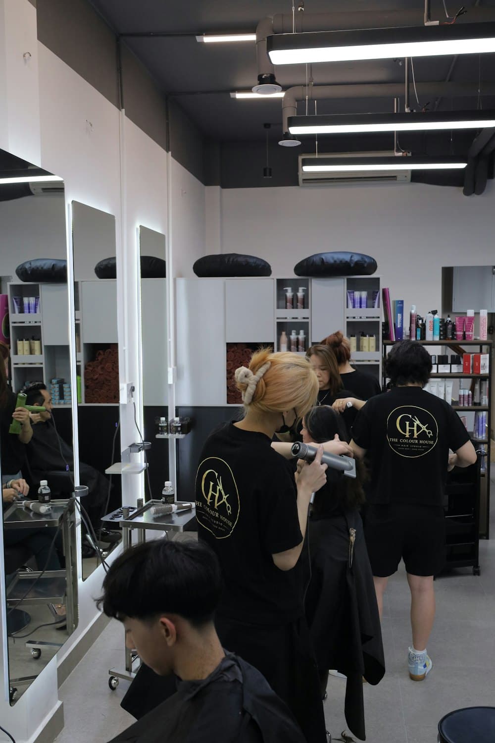 Stylists in black tops working with clients in a bright, modern hair salon